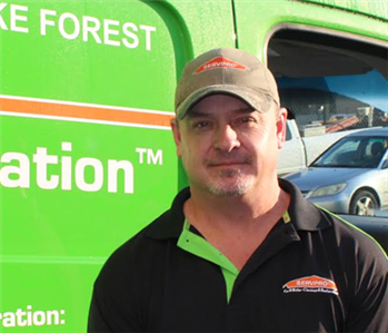 Man wearing hat, with stubble, in front of a green truck