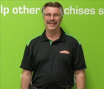 Man smiling wearing a black shirt in front of a green background