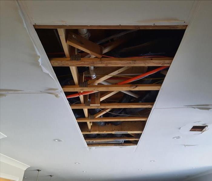 Cut-away ceiling sheetrock exposing water-damaged joists for drying and insulation removal