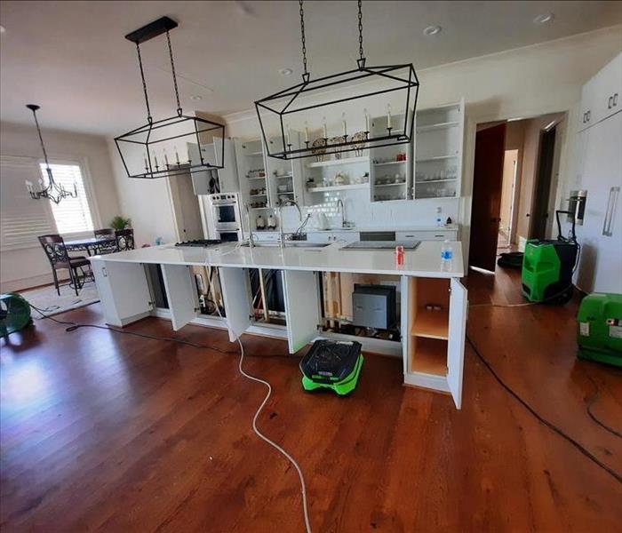 Kitchen and dining area with partially demolished island counter surrounded by four SERVPRO air movers and at least one dehum