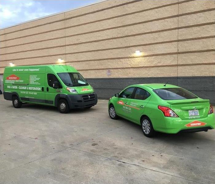 Two SERVPRO vehicles parked in front of a tan wall